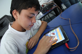a young boy uses his tablet computer in class